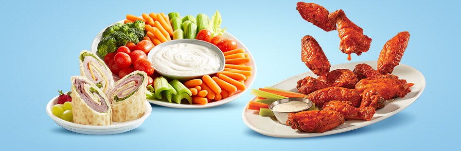 Wraps, vegetable plate, and plate of buffalo wings.