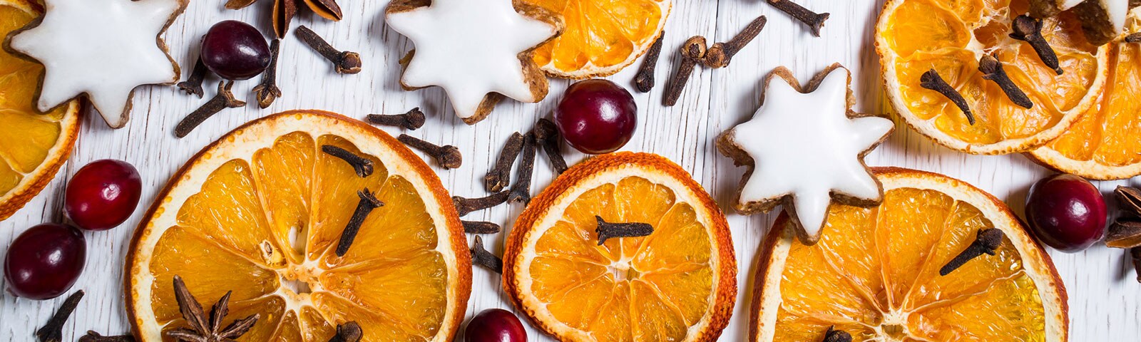 Rustic white, wood background covered with dried orange slices, berries, cinnamon sticks and cloves