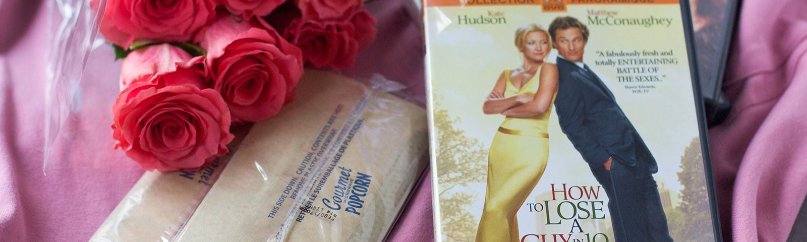 Roses, popcorn and DVDs lying on pink cloth