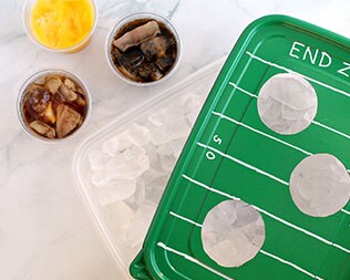 Finished tray: football-themed green rectangle container lid over ice that's ready to serve drinks